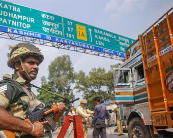 A BSF jawan guards as Jammu and Kashmir Police personnel check the vehicles on the Jammu-Srinagar highway after a truck was seized with arms and ammunition, in Kathua.