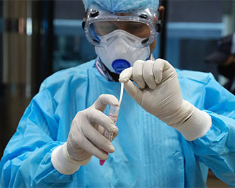 A doctor puts a swab in vial while conducting COVID-19 test
