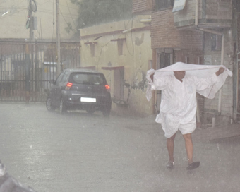 Mathura: A man tries to shield himself during heavy rain in Mathura, on April 17, 2019. (Photo: IANS)