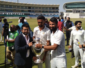 Saurashtra players Cheteshwar Pujara and Jaydev Unadkat holding Ranji Trophy
